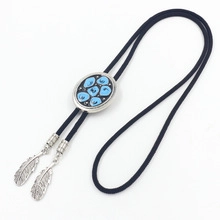 Detail of a black braided leather bolo tie with silver turquoise buckle and feather pendants
