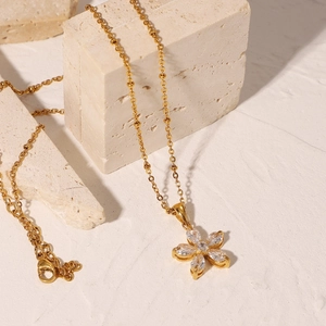 18K gold plated necklace with 16mm white zircon flower pendant on a stone background