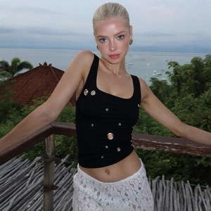 Detail of black slim vest with metal eyelets paired with white lace skirt outdoors