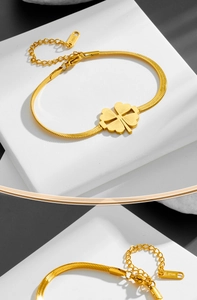 Macro detail of gold stainless steel clover pendant and adjustable snake chain clasp