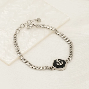 Silver Cuban chain bracelet with anchor hexagon pendant on white marble surface