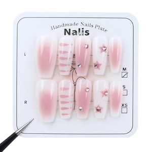 Pink gradient press-on nails with glitter stars and rhinestones on a display card