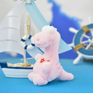 Close-up of a cute pink plush dinosaur keychain pendant in a nautical-themed lifestyle setting