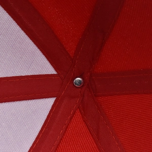 Macro detail of red baseball cap interior with reinforced stitching and metal rivet fastener