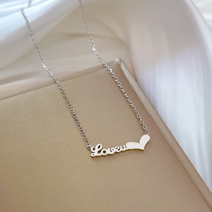 Close-up of silver steel Loveu heart necklace on jewelry stand with silk background