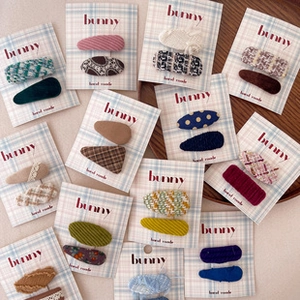 Close-up of handmade fabric bow hair clips in assorted patterns on display cards