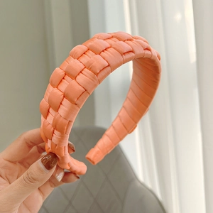 Detailed macro view of vibrant coral orange hand-woven satin headband for women