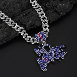 Macro shot of silver Cuban chain with blue iced-out heart and NO LOVE letter pendant