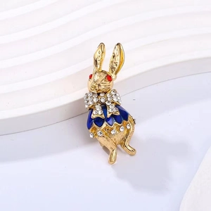 Detail of a gold bunny brooch featuring blue enamel dress and red gemstone eyes