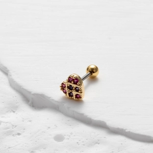 Detail of a golden heart screw-back earring with red and blue zircon stones on a stone base