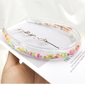 Transparent PVC headband filled with colorful fruit sequins, held against a soft background