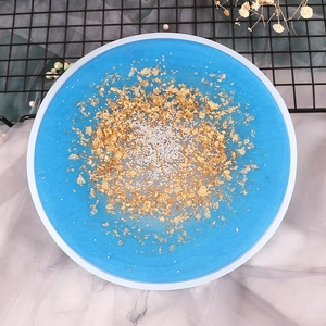 Macro view of handmade round resin tray mold with blue base and gold foil decorative details