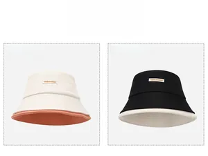 Dettaglio di cappelli a secchiello in tela beige e nera con etichette ricamate