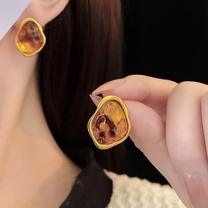 Detail of vintage irregular amber resin earrings with gold metallic frame worn by model