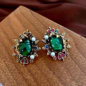 Detailed close-up of emerald green gem and pearls on a vintage gold earring