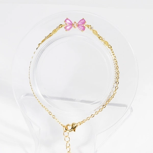 Close-up of pink zircon butterfly charm on a gold-plated delicate bracelet chain