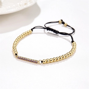 Detailed shot of gold plated bar bracelet with purple zircon and black adjustable rope