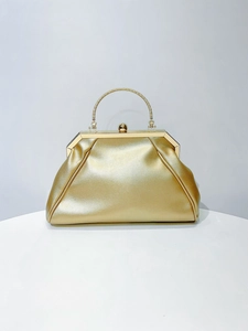 Detail of elegant gold trapezoid evening bag with textured metal handle and ball clasp closure