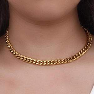 Detail view of a stylish gold Cuban link chain necklace worn on a model neck