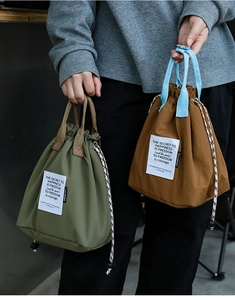 Detail showing army green and brown drawstring lunch bags with durable woven handles