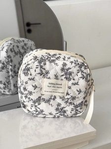 Quilted floral makeup bag with black flower prints on white base and zipper closure