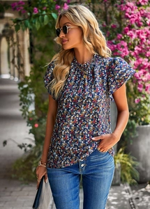 Detailed view of floral pattern on navy blue short sleeve blouse worn in natural light