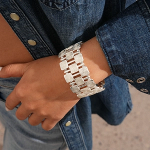 Detailed view of wide silver metal bracelet with ethnic square swirl relief patterns
