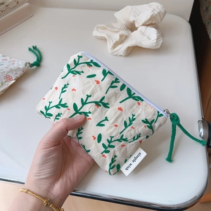 Close-up of floral cotton pouch with metal zipper and simple wish label