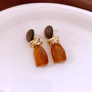 Macro shot of vintage wood and amber resin drop earrings on a white ceramic plate