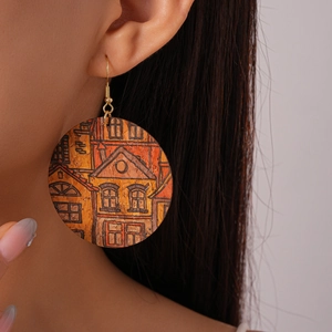 Close-up of bohemian leather earrings with architectural print and golden ear hooks