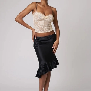 Detailed view of women's black satin midi skirt with irregular ruffled hem and side ruched detail