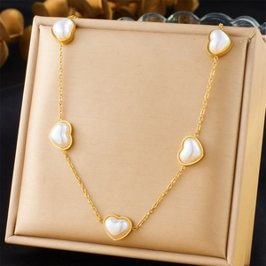 Vue détaillée du collier doré avec cinq perles en forme de cœur dans un coffret cadeau chic