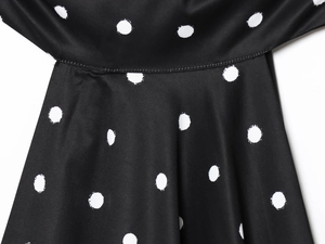 Close-up of black satin fabric with white polka dots and neat stitching details