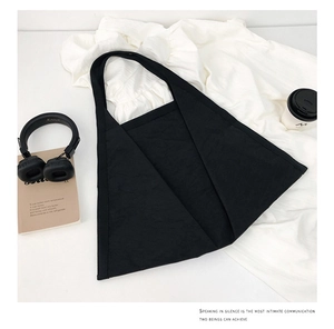 Lifestyle shot of black canvas tote bag with headphones, coffee, and a minimalist aesthetic