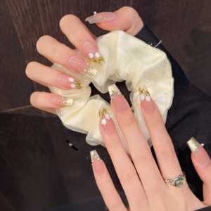 Détail de faux ongles longs avec fleurs de lys, perles et chouchou assorti inclus