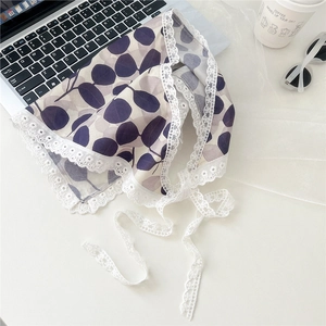 Flat lay of floral triangle scarf with lace trim next to a laptop and coffee cup