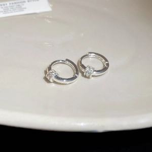 Macro shot of silver-plated hoop earrings with sparkling cubic zirconia on ceramic tray