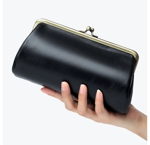 Detail of premium black leather clutch featuring a vintage brass metal kiss-lock frame