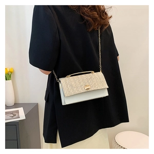 Detail of hand-woven texture and gold chain on cream white crossbody bag shown on a model