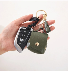 Detail of green litchi grain leather AirPods case with gold buckle and matching tassel