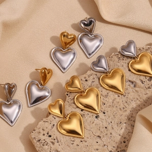 Detailed close-up of double-layered heart stud earrings in 18K gold and silver finish