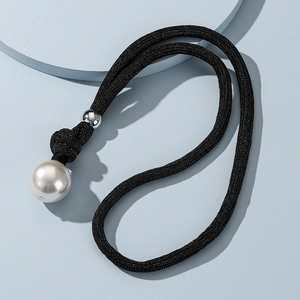 Detailed macro view of a large white pearl pendant on a black woven rope necklace