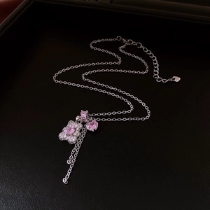 Close-up of bear pendant with pink heart zircon and tassels on silver necklace