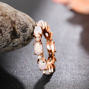Vue macro d'une bague éternité en or rose avec opales blanches et oxydes de zirconium