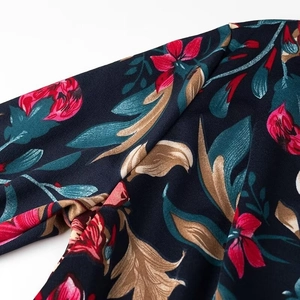 Detail of floral print on dark blue polyester fabric with vibrant red flower patterns