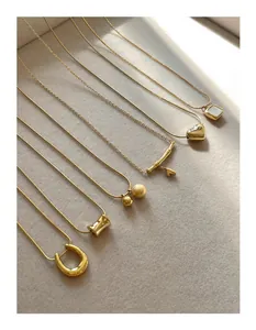 Flat lay of multiple gold titanium necklaces with heart and bead pendants on beige velvet