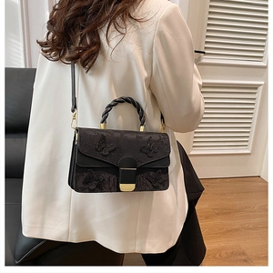 Fashionable black crossbody bag with 3D butterfly embroidery shown on a model