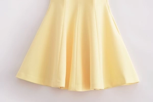 Detail of light yellow dress with high-quality multi-panel stitching and wide hem
