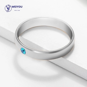 Close-up of a minimalist silver stainless steel ring featuring a round blue birthstone inlay