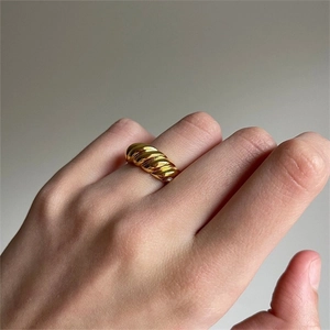 Polished gold-plated croissant dome ring worn by a model on index finger